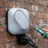 Etrel INCH Core Wallbox mit Ladebuchse auf Steinwand mit Nutzer der Smartphone und App zum smart charging nutzt