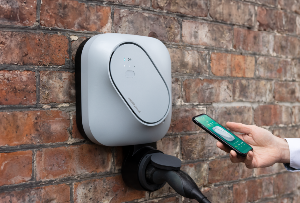 Etrel INCH Core Wallbox mit Ladebuchse auf Steinwand mit Nutzer der Smartphone und App zum smart charging nutzt